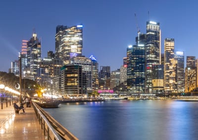 Illuminated Sydney waterfront buildings and reflections at blue hour.