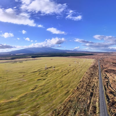 A panoramic view of green highlands under a blue sky with clouds.