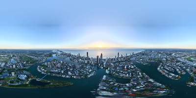 A panoramic view of a city skyline at sunrise over waterways.